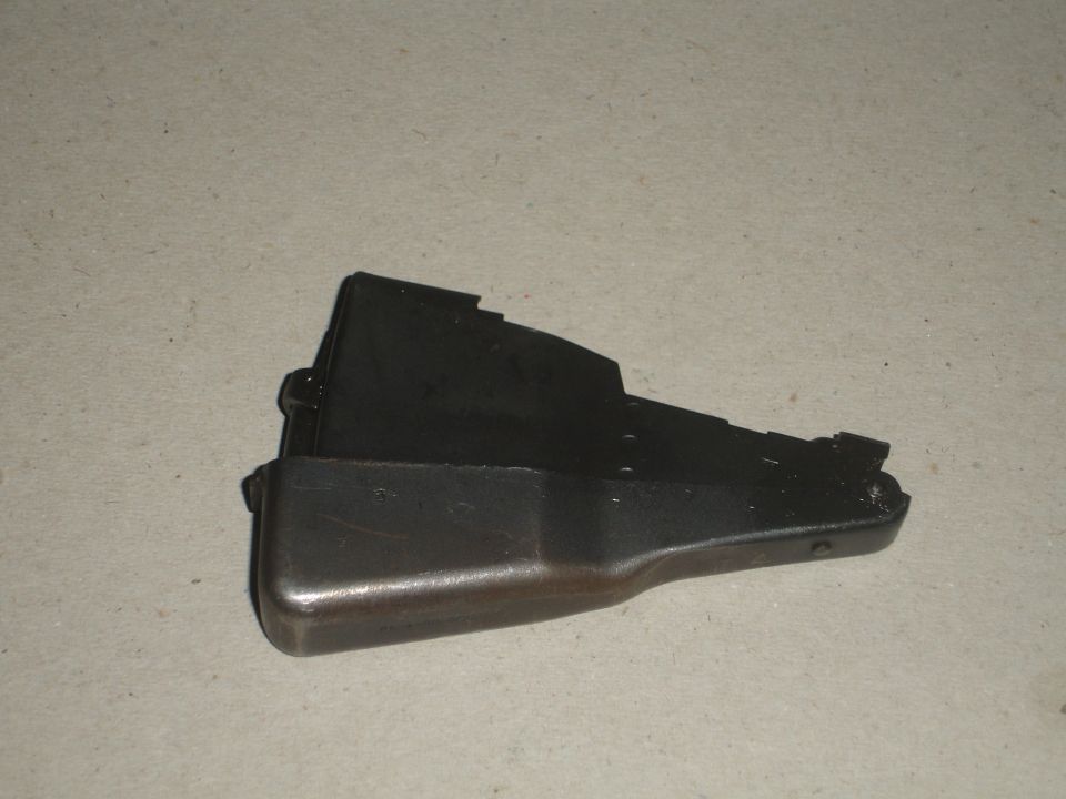 Black metal automotive part with a silvered edge, resting on a concrete surface