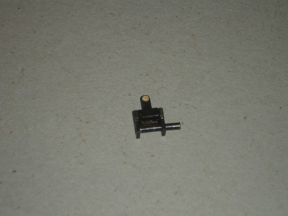 Small black metal mechanical part with a pin extending from the side