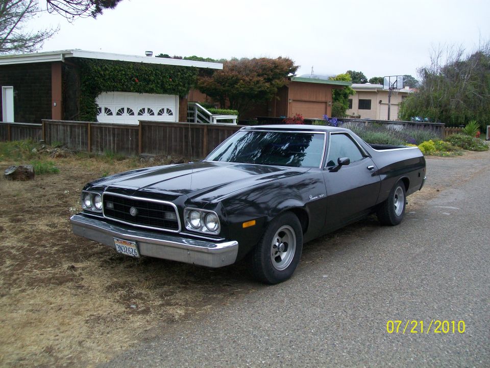 Black Ford Ranchero car-pickup parked, front 3/4 view, chrome grille and mag wheels.
