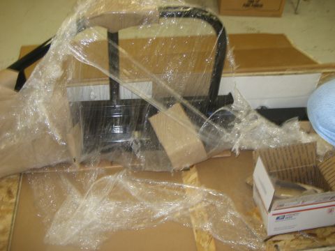 1978 Ford Bronco - A black metal part, likely a bumper component, is seen wrapped in plastic packaging.