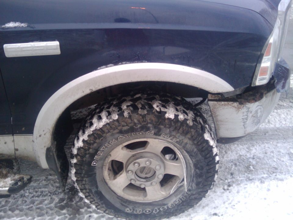 Dark blue 2005 Ford F-250 front fender and wheel with snow on tire