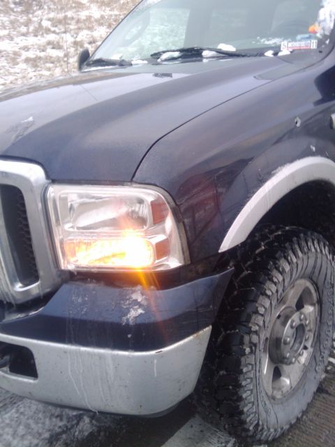 2005 Ford F-250 - Front corner of a dark blue 2005 Ford F-250 pickup truck shows the headlight and turn signal on.
