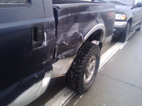 2005 Ford F-250 - This 2005 Ford F-250 shows extensive damage to its rear quarter panel and side. The FX4 badging is visible.