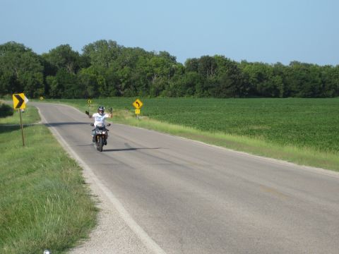 2008 Yamaha FZR1000 - A motorcyclist enjoys a ride on a sunny day, with arms outstretched on a rural road.
