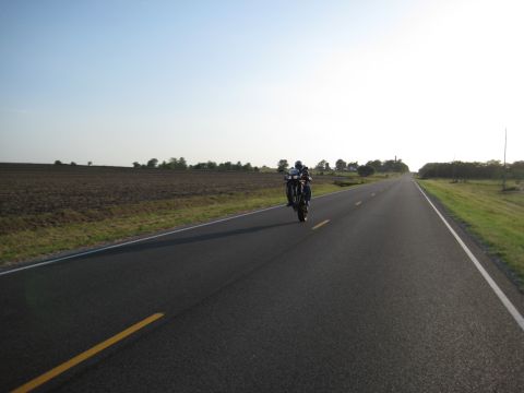 2008 Yamaha FZR1000 - A motorcycle is shown performing a wheelie on an open road under a clear sky.
