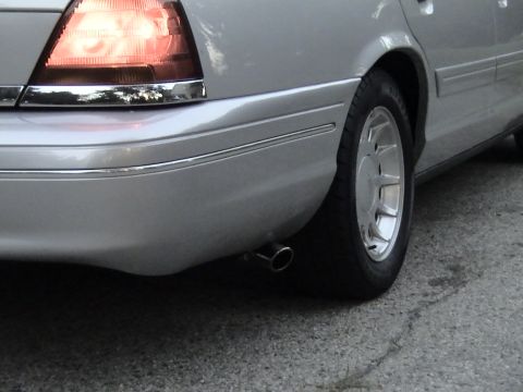 2000 Ford Crown Victoria - Detail of a silver sedan's rear corner showing the taillight, dual-spoke alloy wheel and chrome exhaust tip.