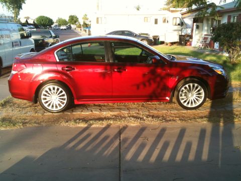 2010 Subaru Legacy - Side profile of a red 2010 Subaru Legacy sedan parked on a sunny day.
