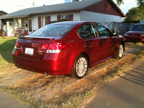 2010 Subaru Legacy - Red 2010 Subaru Legacy sedan parked on a driveway, with another vehicle visible in the background.