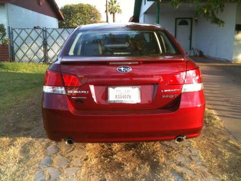 2010 Subaru Legacy - The rear of a red Subaru Legacy 2.5GT is shown, with a license plate and model badging visible.