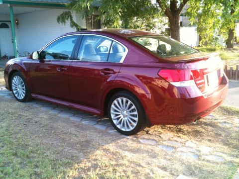2010 Subaru Legacy - Maroon 2010 Subaru Legacy sedan parked on stone pavers in front of a house.