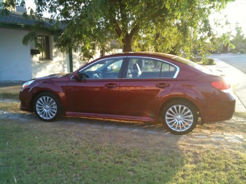 2010 Subaru Legacy - Side view of a red 2010 Subaru Legacy sedan parked on a grassy area.