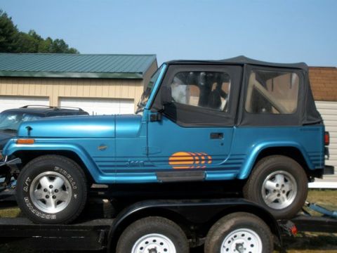 1991 Jeep YJ - Side view of a blue 1991 Jeep YJ on a trailer, ready for transport.