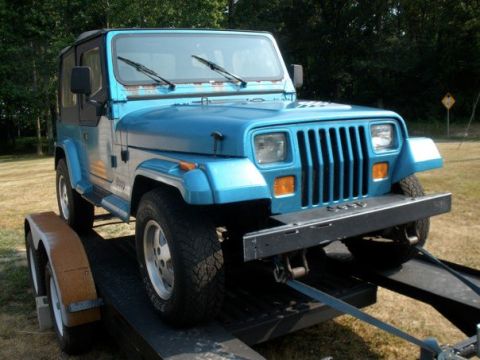 1991 Jeep YJ - A blue Jeep Wrangler is secured to a trailer, ready for transport.