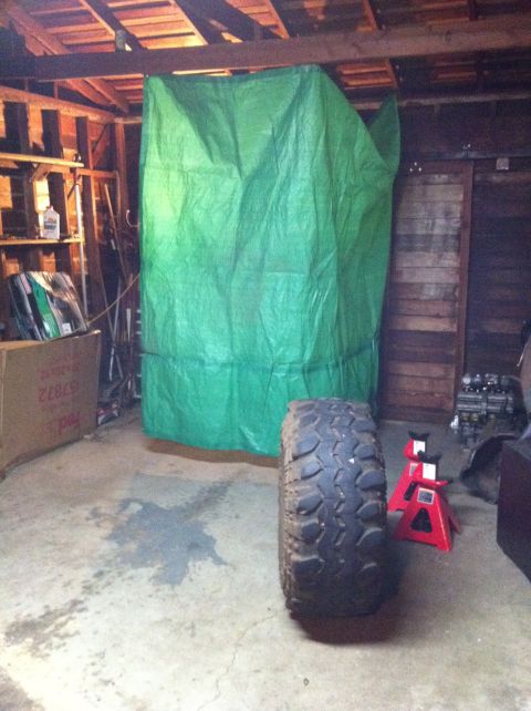 1989 Ford Bronco - Garage scene with a large tire and a tarp-covered item, suggesting a project in progress.