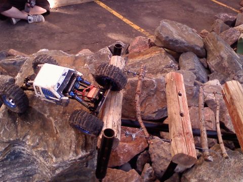 1996 Ford Bronco - A remote control rock crawler is shown attempting to traverse a challenging obstacle made of logs and rocks.