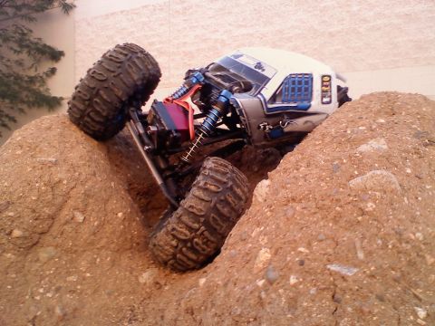 1996 Ford Bronco - This remote-controlled rock crawler is navigating a challenging dirt terrain, with its suspension system clearly visible.