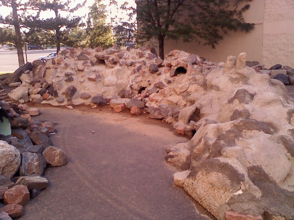 rock formation with holes and a car in the background