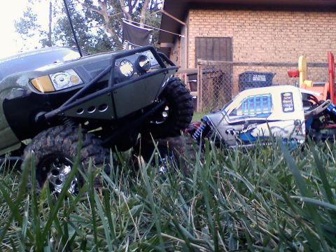 1996 Ford Bronco - Two remote-controlled vehicles are parked in the grass, one a green off-road buggy and the other a white truck with custom graphics.