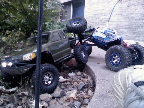 1996 Ford Bronco - Two remote control rock crawlers are positioned on a rocky surface, with one appearing to climb over the other.