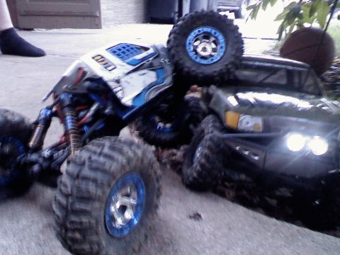1996 Ford Bronco - Two RC rock crawlers are positioned on the ground, with one partially obscuring the other.