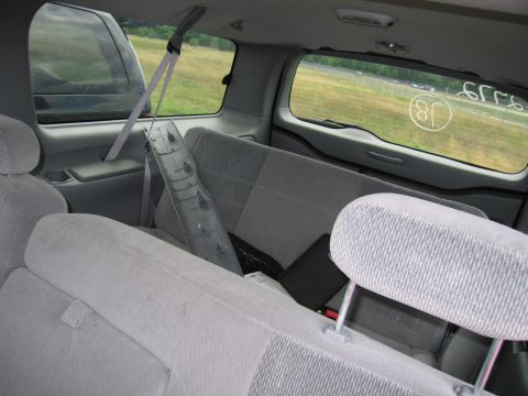 2001 Ford Crown Victoria - The interior of a van shows gray fabric seats and a long plastic trim piece on the floor.
