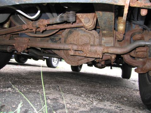 2001 Ford Crown Victoria - A low-angle shot reveals the heavily rusted undercarriage of a vehicle, focusing on the suspension components and differential.