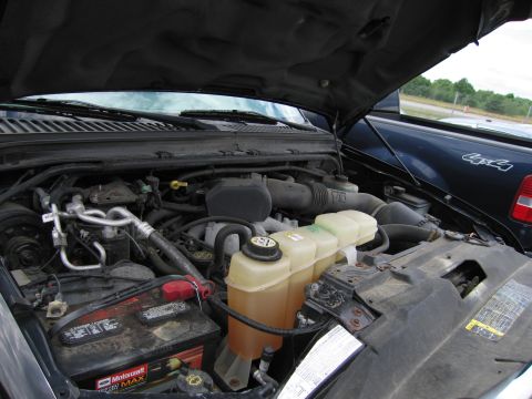 2001 Ford Crown Victoria - The engine bay of a truck is shown, with another truck visible in the background.