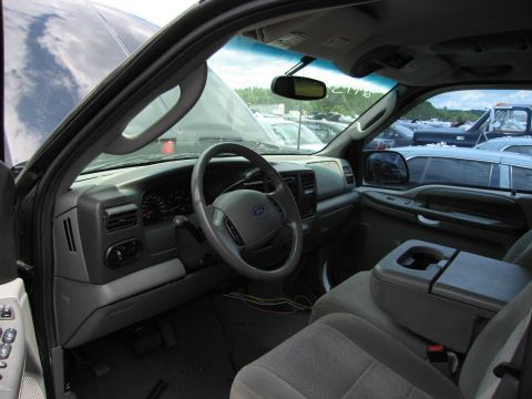 2001 Ford Crown Victoria - Interior view of a 2003 Ford Excursion, with dashboard, steering wheel, and seats visible. Other vehicles are seen in the background.