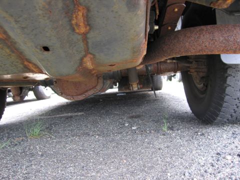2001 Ford Crown Victoria - Undercarriage view of a heavily rusted vehicle, focusing on the rear axle and fuel tank.