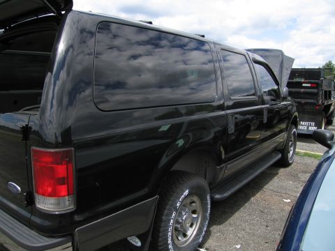2001 Ford Crown Victoria - A black SUV is parked next to a dump truck with 'PAYETTE TRUCK BODY' written on it.