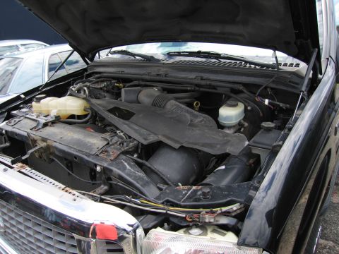 2001 Ford Crown Victoria - The engine bay of a black truck is visible, with another vehicle parked nearby.