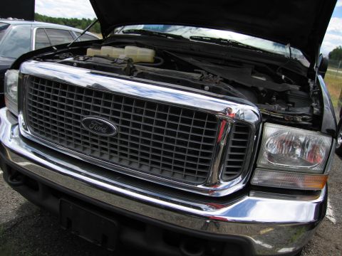 2001 Ford Crown Victoria - Front view of a black Ford Excursion, hood open, revealing the engine bay and prominent Ford grille.