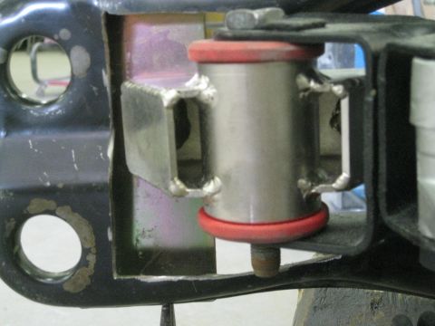 1994 Ford Probe - Close-up view of a suspension bushing assembly, red rubber isolators and a metal bracket. Text from Supermotors.net is visible.