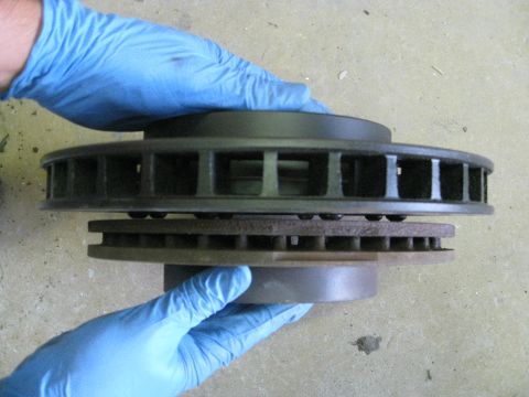 1994 Ford Probe - Two brake rotors are held by gloved hands, one on top of the other.