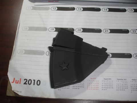 1989 Ford Bronco - A black plastic part with a star emblem rests on a calendar from July 2010.