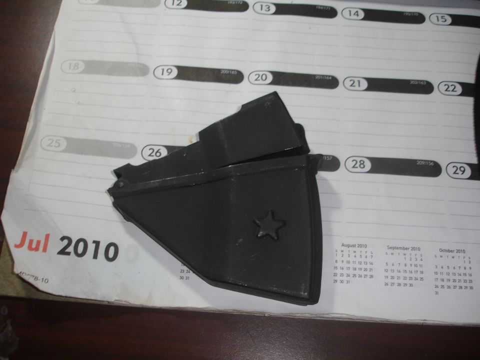 Black plastic part with a star emblem on a calendar dated July 2010