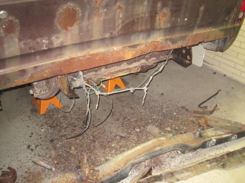 1979 Ford Bronco - Heavily rusted vehicle frame and undercarriage components are visible, supported by jack stands.