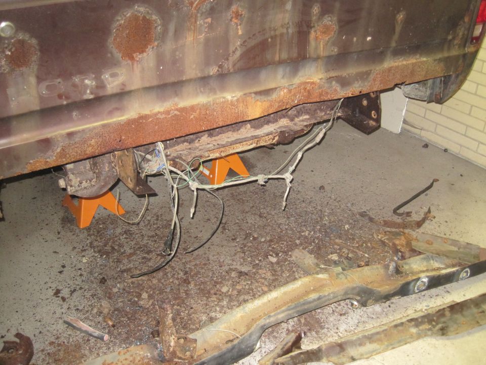 rusted vehicle frame and undercarriage supported by orange jack stands