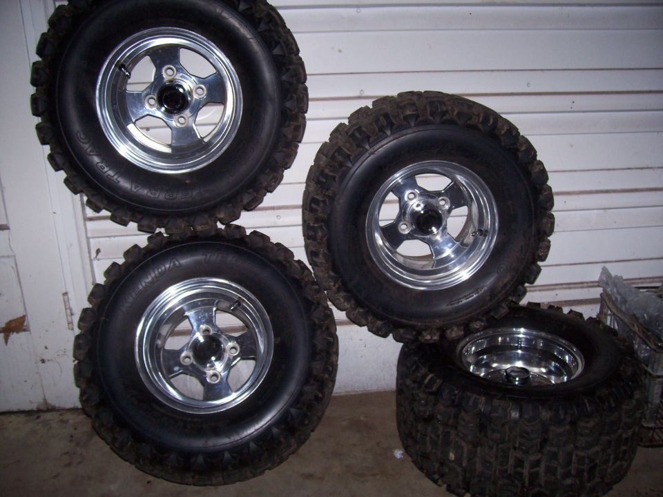 four off-road tires with chrome rims stacked