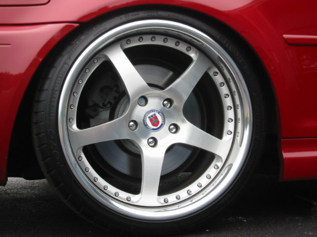 Polished silver five-spoke HRE wheel on a red car with low-profile tire
