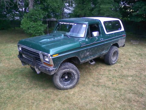 1979 Ford Bronco - Green Ford Bronco with white top, lifted with off-road tires and a "Let's Pit Stop" sticker.