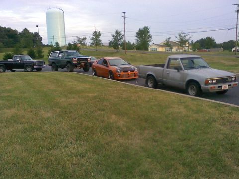 1979 Ford Bronco - A line of four vehicles, including two trucks, an SUV, and a sedan, are parked on a paved surface.
