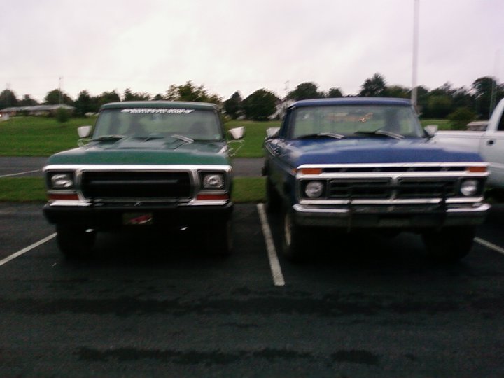 Green and blue pickup trucks parked front-end out in a lot. The green truck is on the left