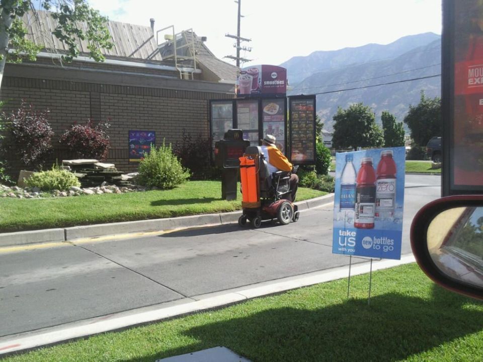 Person on mobility scooter at drive-thru with mountains in background