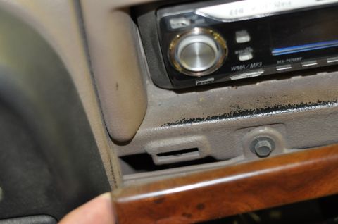 1996 Ford Bronco - Close-up of a car's dashboard reveals an aftermarket stereo and wood grain trim.