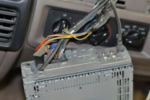 1996 Ford Bronco - Wiring for a car stereo is exposed, with the unit partially removed from the dashboard.