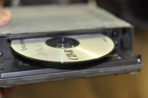 1996 Ford Bronco - A CD-R disc with handwriting is being placed into a drive mechanism.