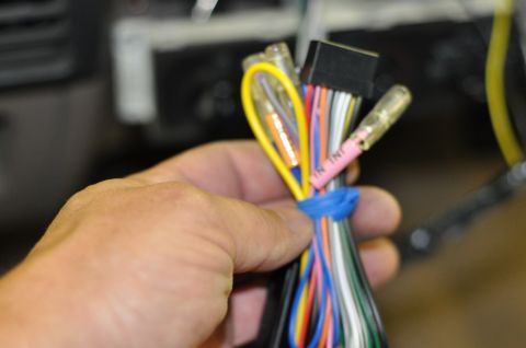 1996 Ford Bronco - Close-up of a hand holding a car stereo wiring harness with multiple colored wires.