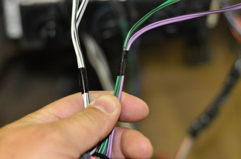 1996 Ford Bronco - A hand holds a wiring harness, showing electrical tape used to secure connections.