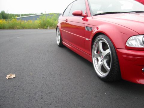1998 Ford Crown Victoria - A red BMW M3 coupe is parked on asphalt, with a grassy area and building in the background.